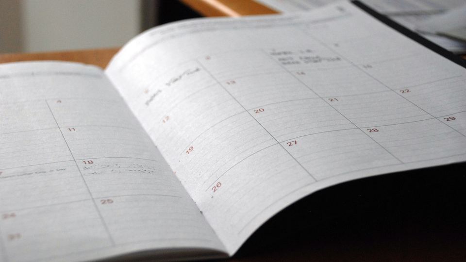 Agenda mensuel ouvert sur table en bois — le suivi régulier de votre présence digitale