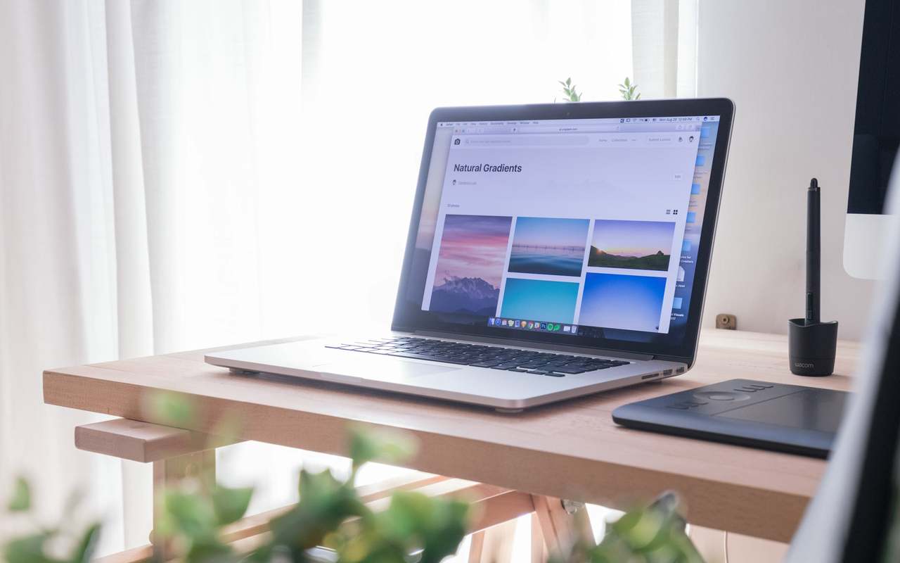 Bureau d'artisan digital — ordinateur portable ouvert sur un plan de travail en bois clair, ambiance Toulouse Occitanie