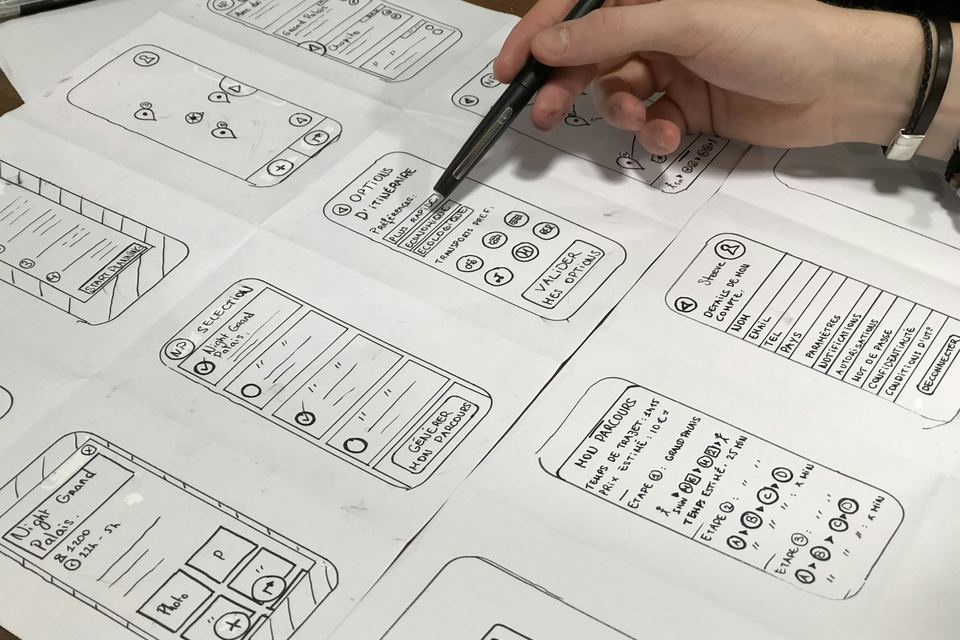 Main qui dessine sur papier — l'épure du métier d'artisan digital, où chaque trait compte