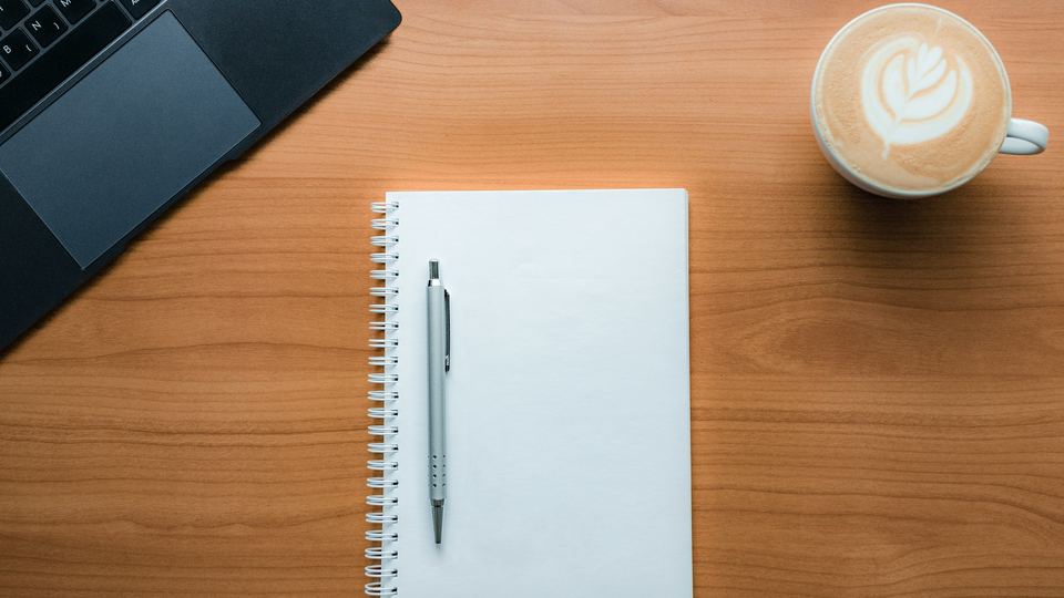 Café, carnet et stylo sur table en bois — moment d'échange artisanal pour un diagnostic digital sans jargon