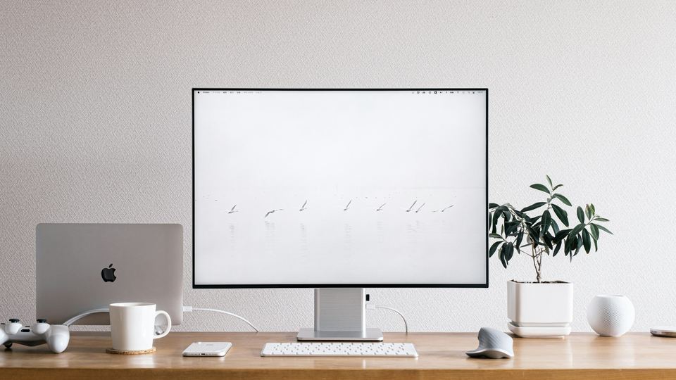 Bureau d'artisan digital — écran iMac sur plan de travail bois, ambiance création de site internet pour TPE Toulouse